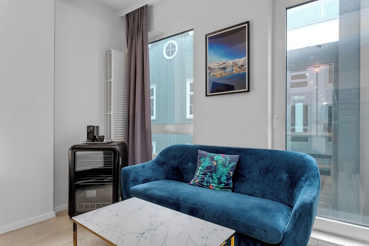 A modern living room with a blue sofa, a marble coffee table, and a black heater unit.