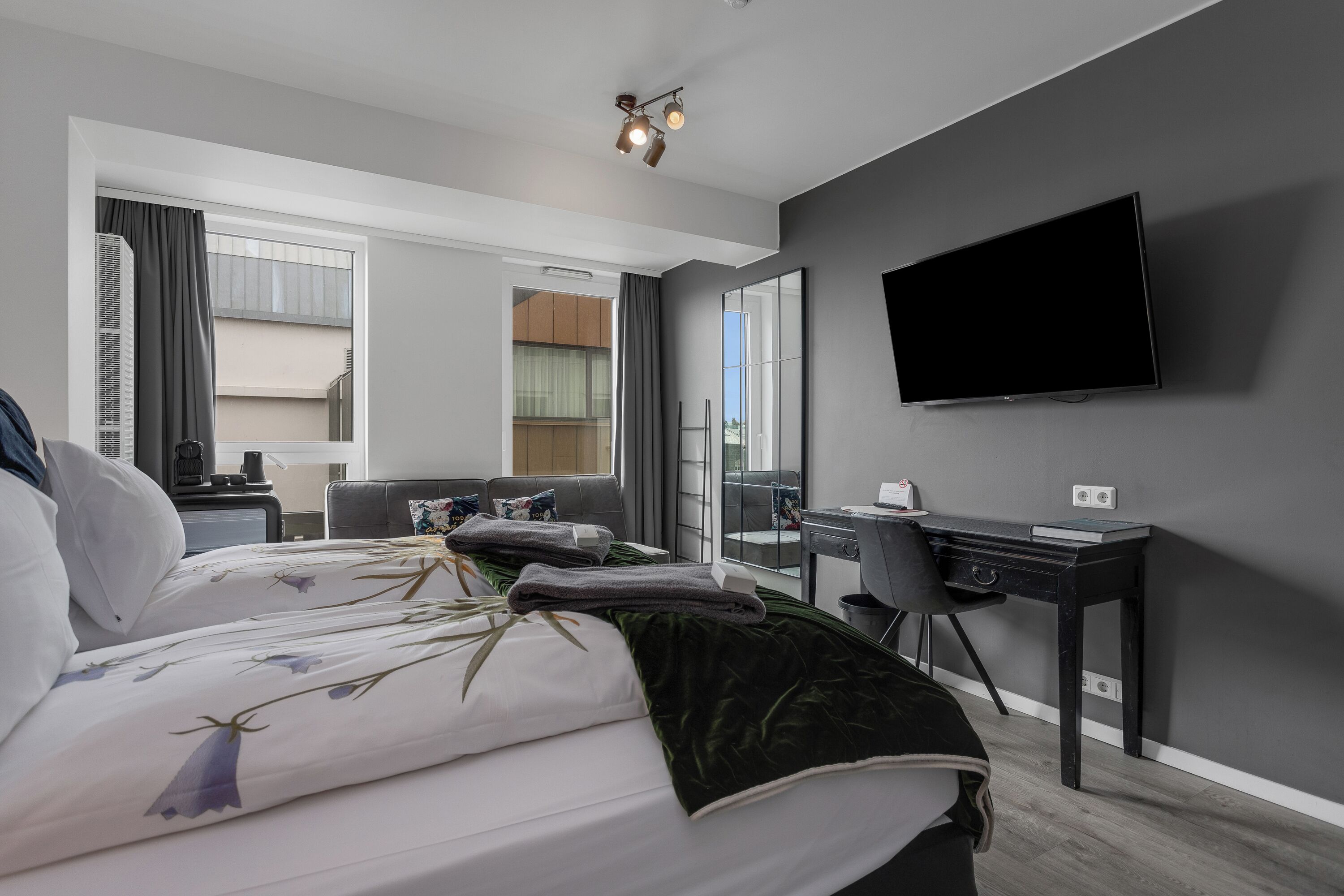 A modern hotel room with a large bed, a desk, and a flat-screen TV.