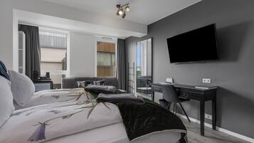 A modern hotel room with a large bed, a desk, and a flat-screen TV.