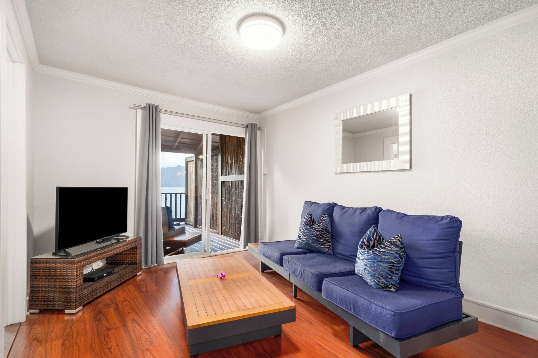 Una sala de estar moderna con un sofá azul, una mesa de centro de madera y un televisor sobre un mueble de madera.