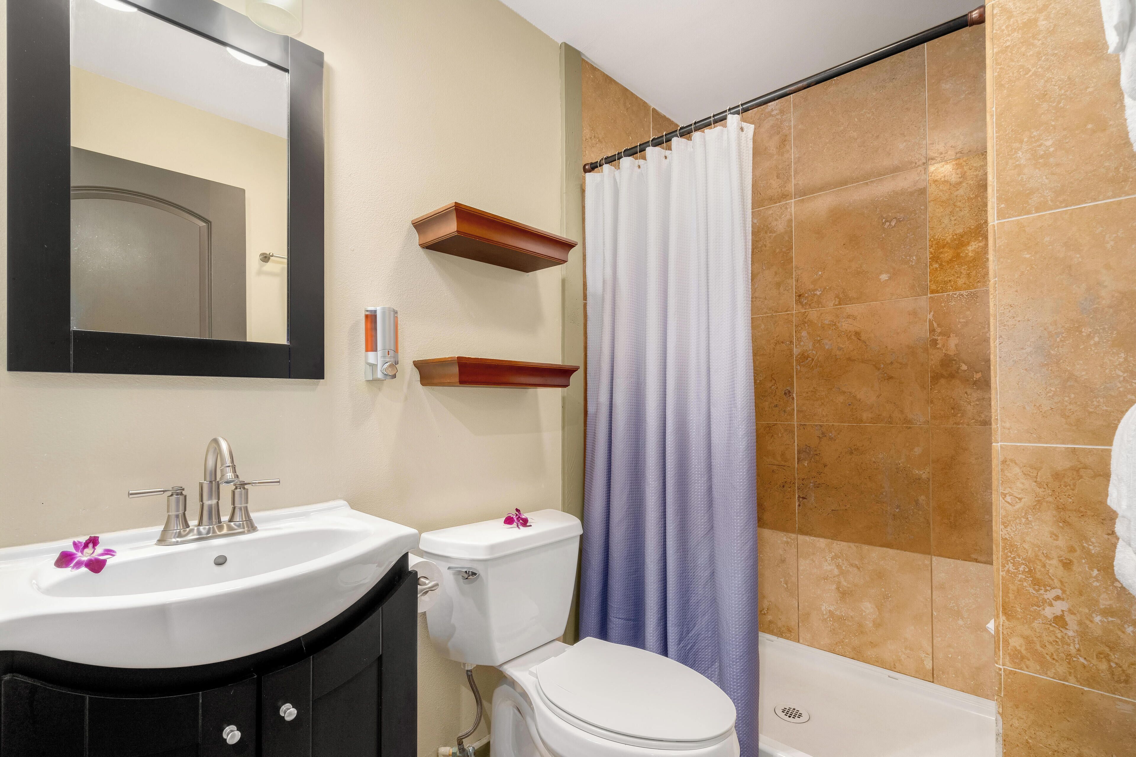A bathroom with a white sink, a toilet, and a shower curtain.