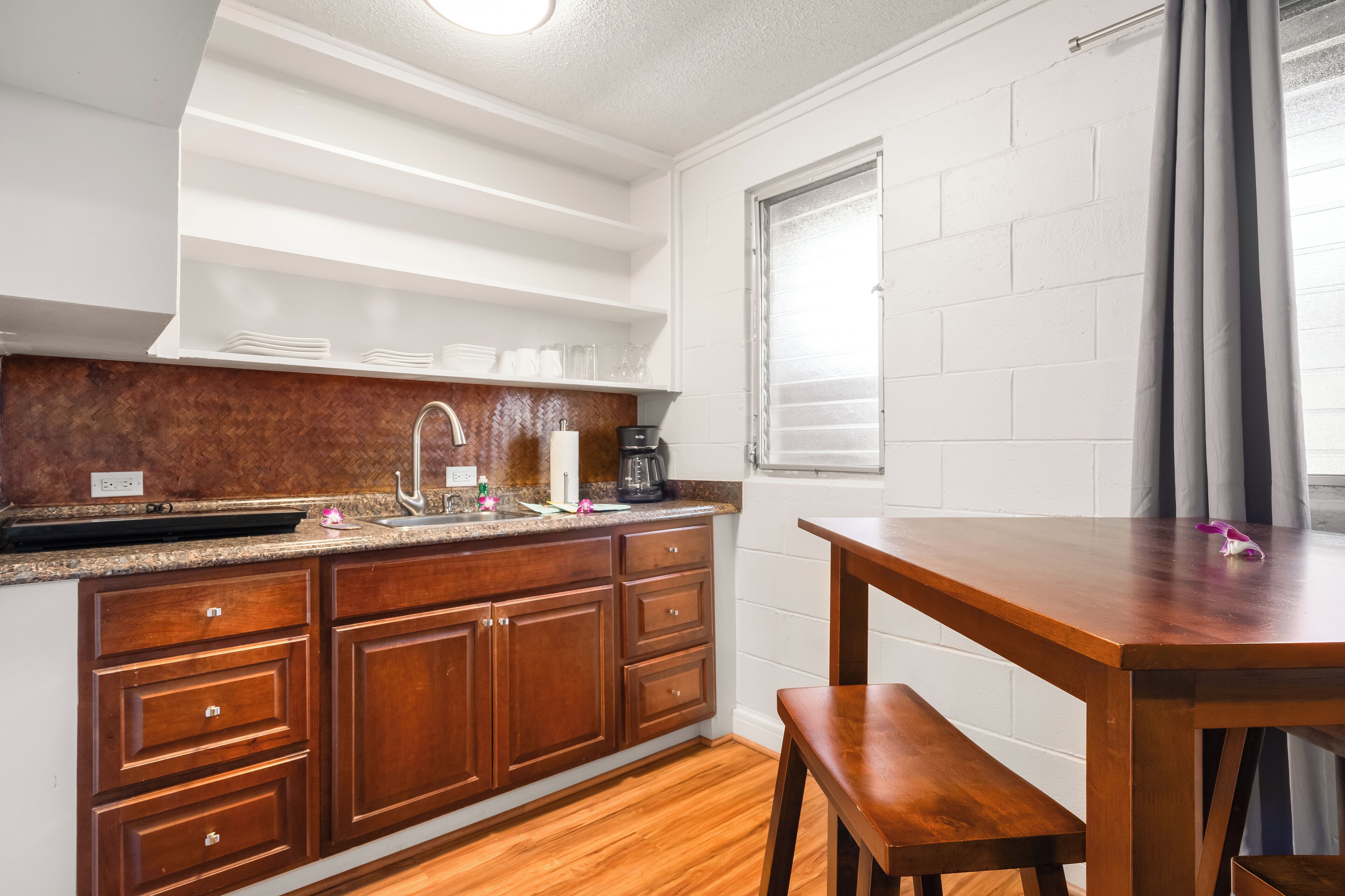A compact kitchen with wooden cabinets, a granite countertop, and a built-in oven.