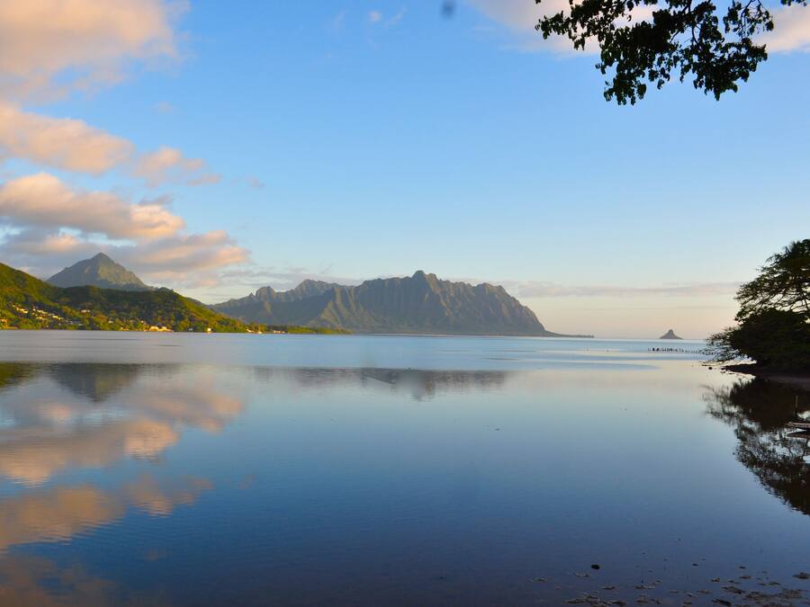 A calm lake with mountains in the background and a clear sky.