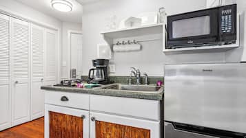 Una cucina compatta con frigorifero in acciaio inox, macchina del caffè, forno a microonde e lavandino.