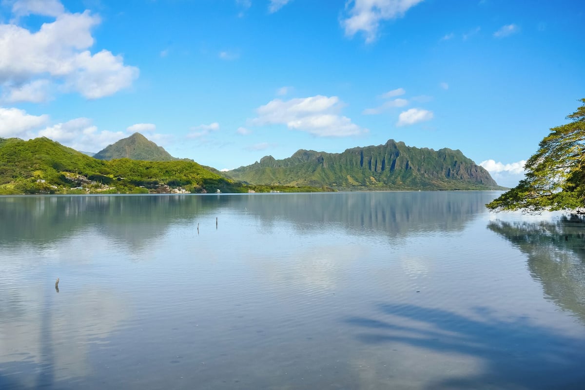 A calm lake with mountains in the background and a clear sky.