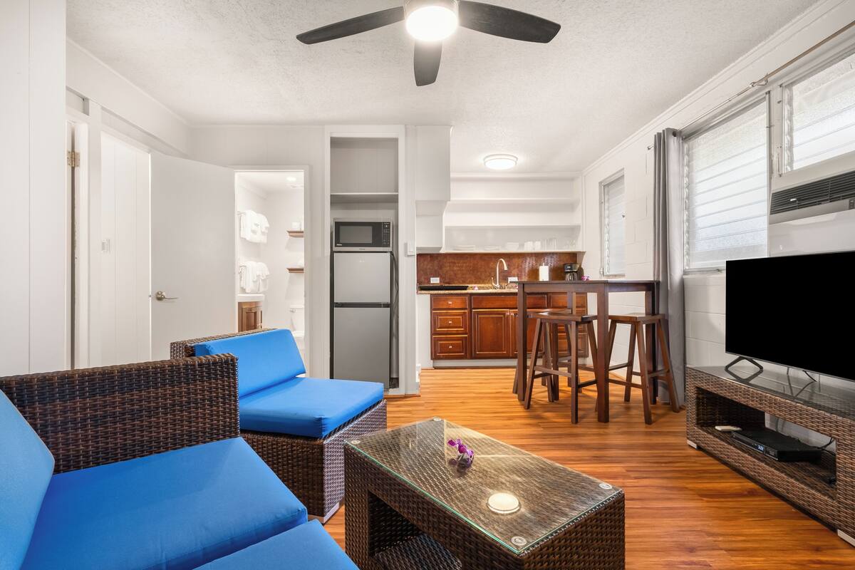 A compact living space with a kitchenette, a dining area, and a seating area with blue cushions.