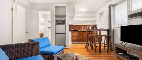 A compact living space with a kitchenette, a dining area, and a seating area with blue cushions.