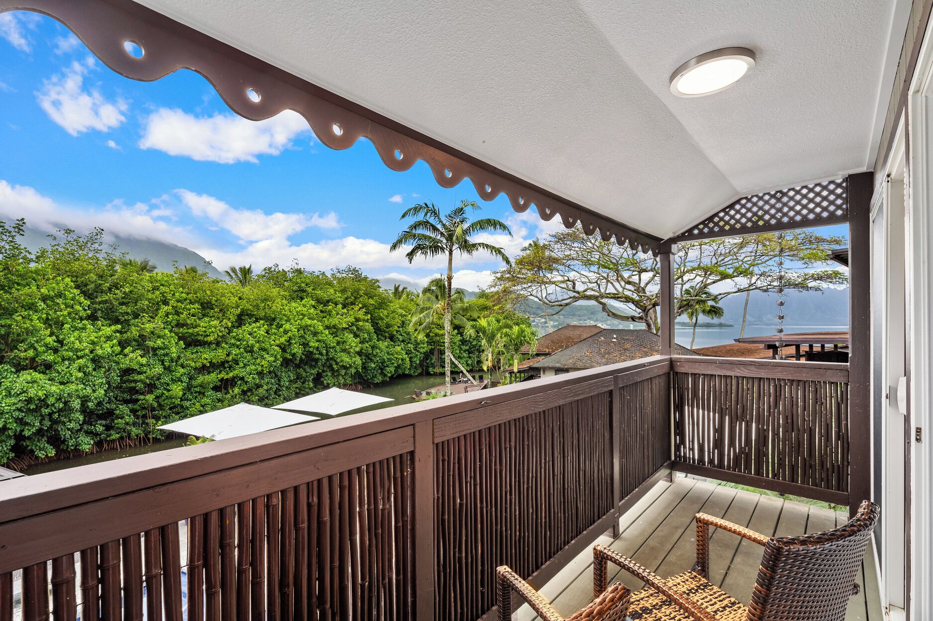 A covered outdoor area with a view of lush greenery and a body of water.