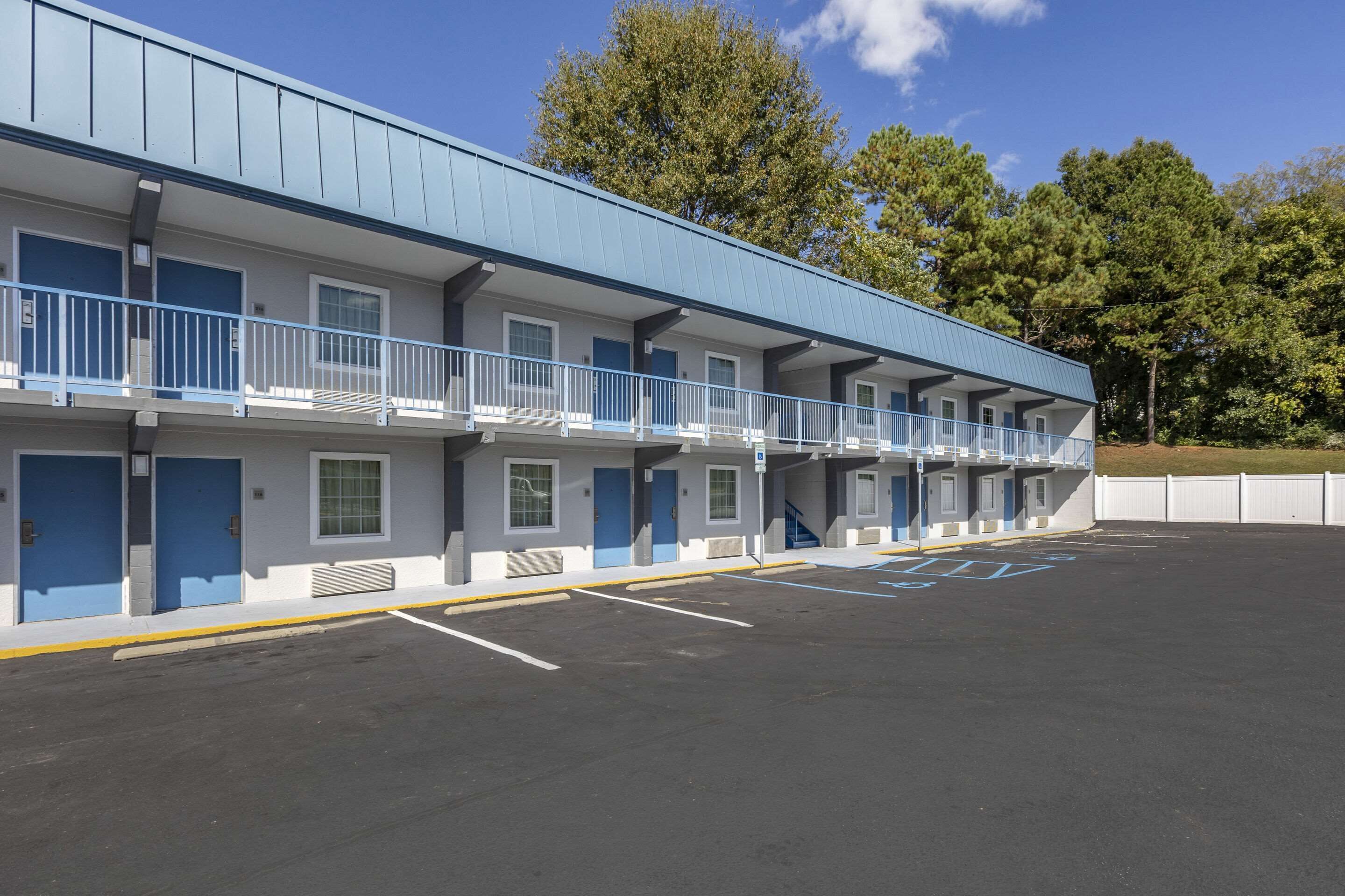 Un motel con una hilera de habitaciones, cada una con un balcón y una puerta azul.
