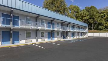A motel with a row of rooms, each with a balcony and a blue door.