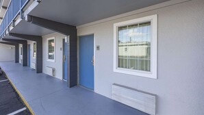 Una hilera de edificios residenciales con una puerta azul, una ventana blanca y una rejilla en la pared.