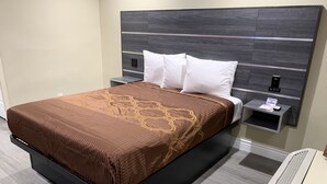 A modern hotel room with a large bed, a nightstand, a bedside table, and a built-in air conditioning unit. - Pacific Inn Anaheim (Anaheim)