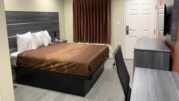 A modern hotel room with a large bed, a desk, and a television. - Pacific Inn Anaheim (Anaheim)