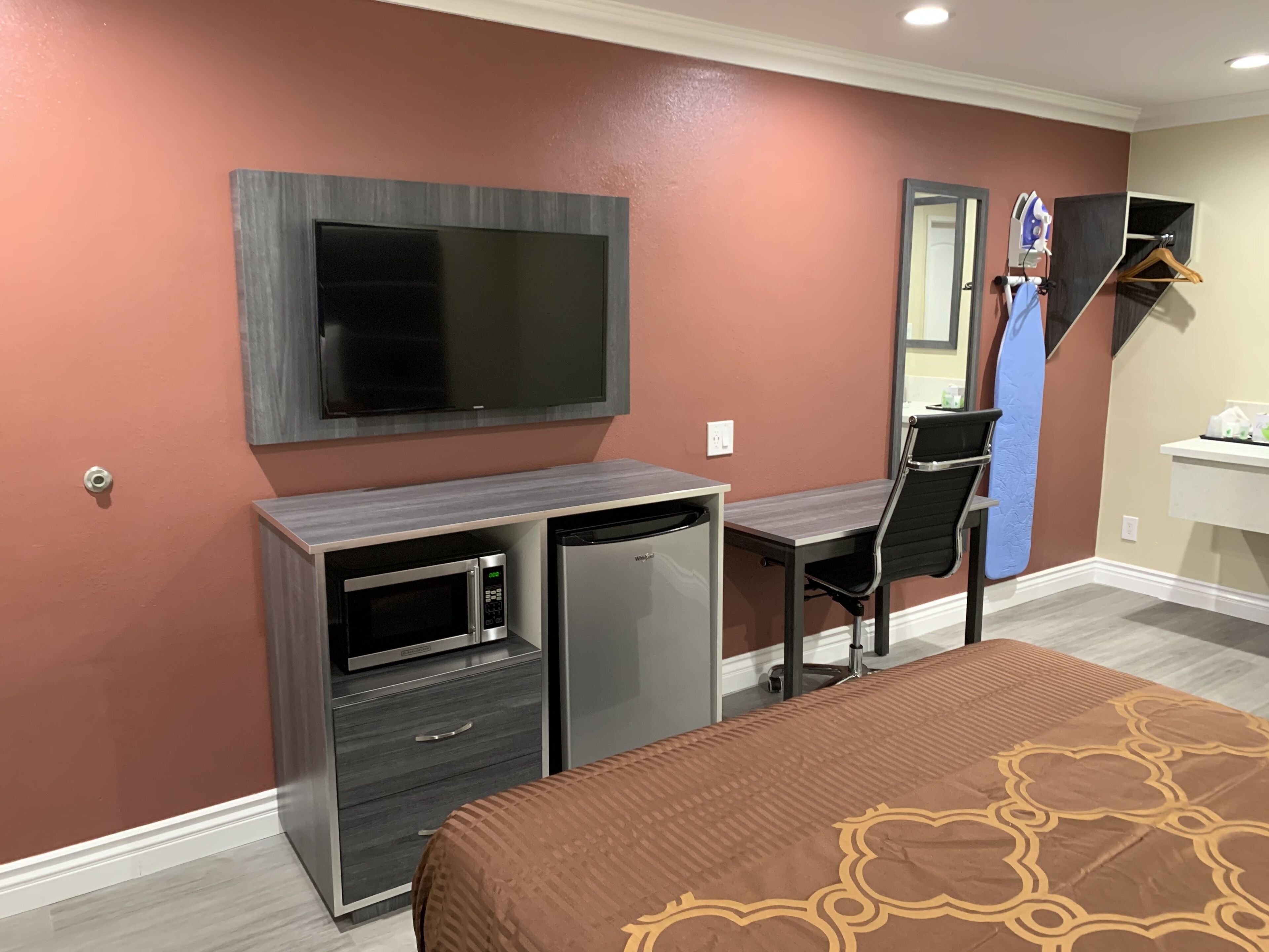 A hotel room with a bed, a desk with a computer, a microwave, and a television.