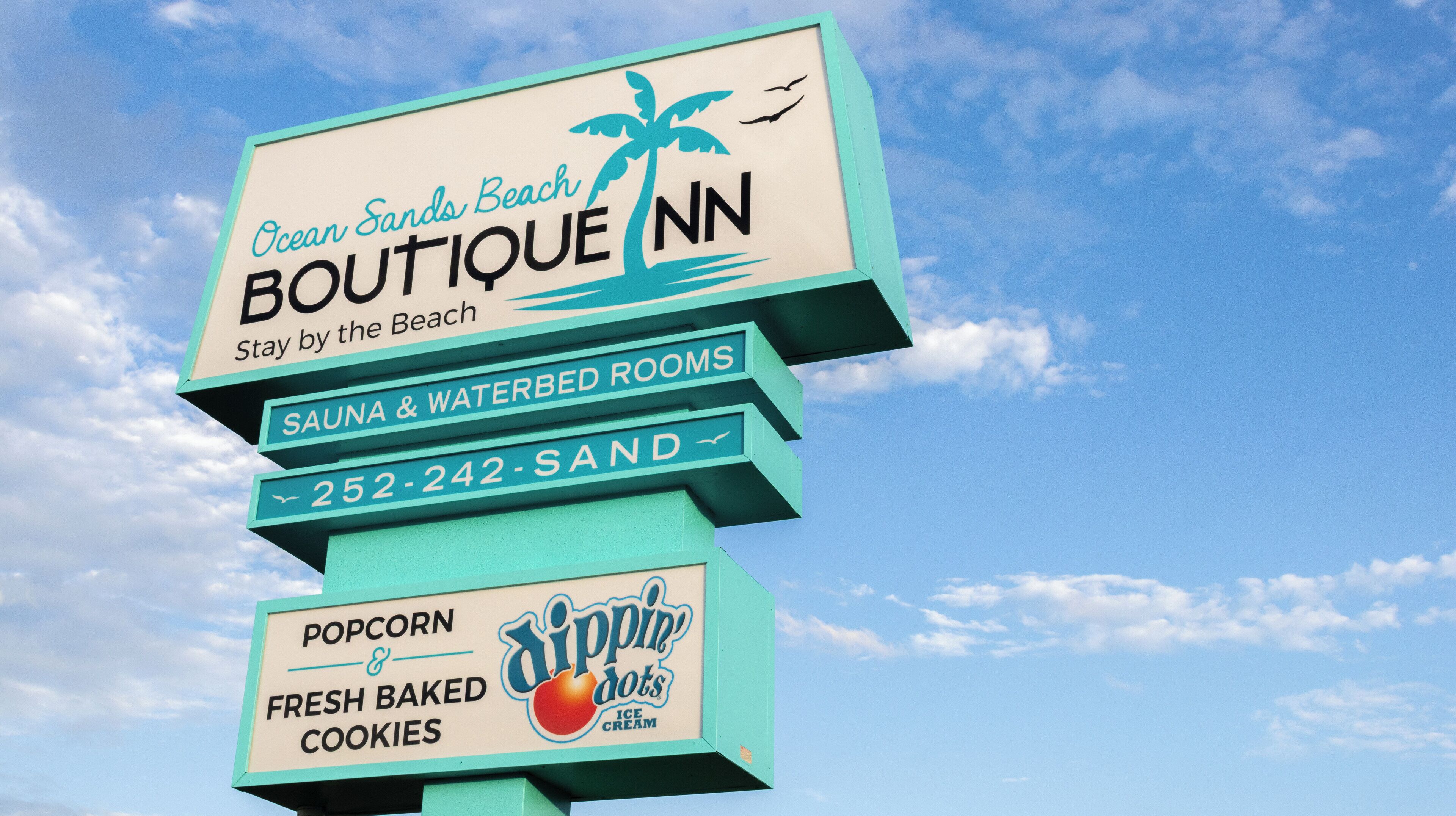 A sign for Ocean Sands Beach Boutique with amenities including sauna, waterbed rooms, and a phone number.