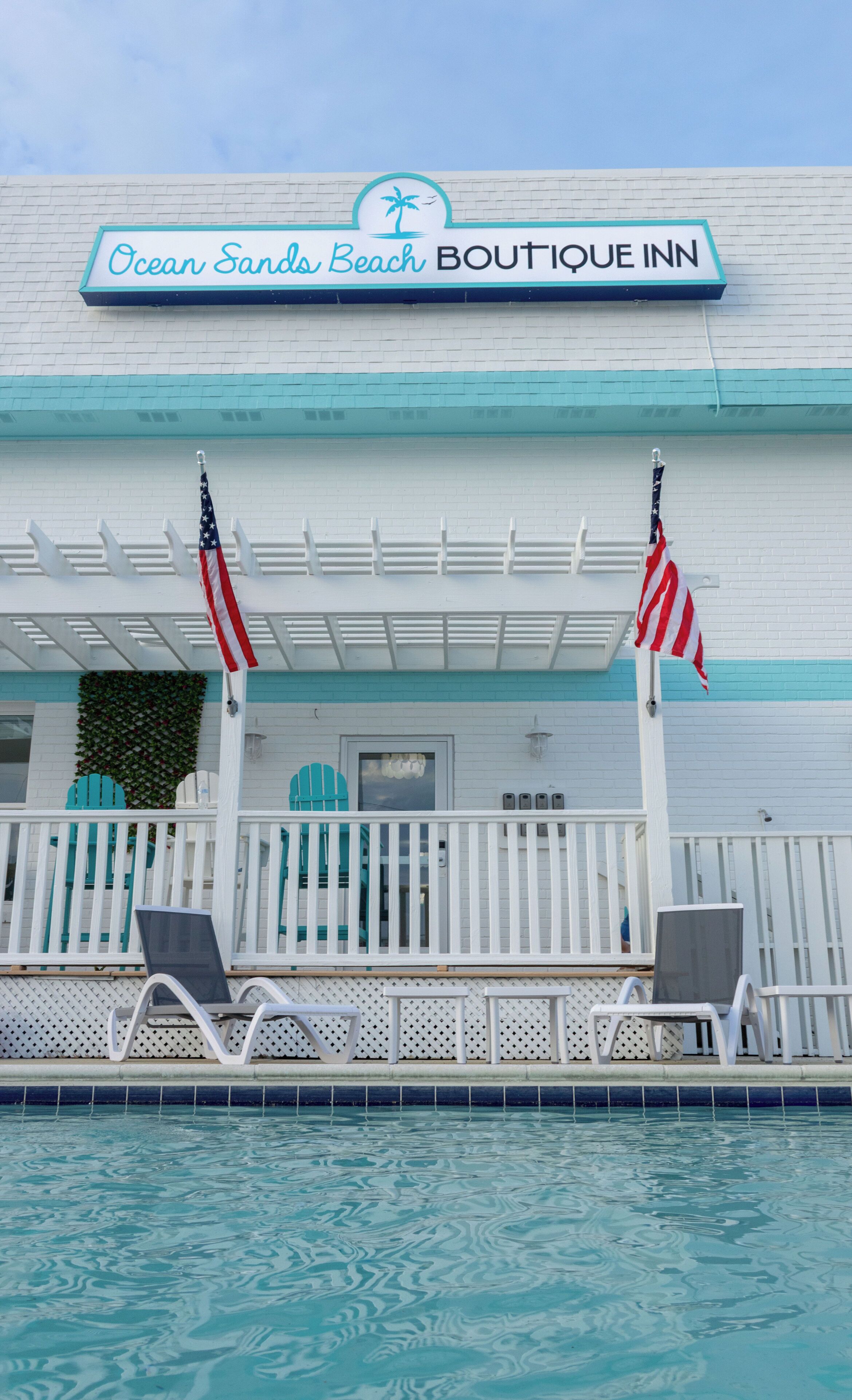 A building with a sign reading 'Ocean Sands Beach Boutique Inn' and two American flags.
