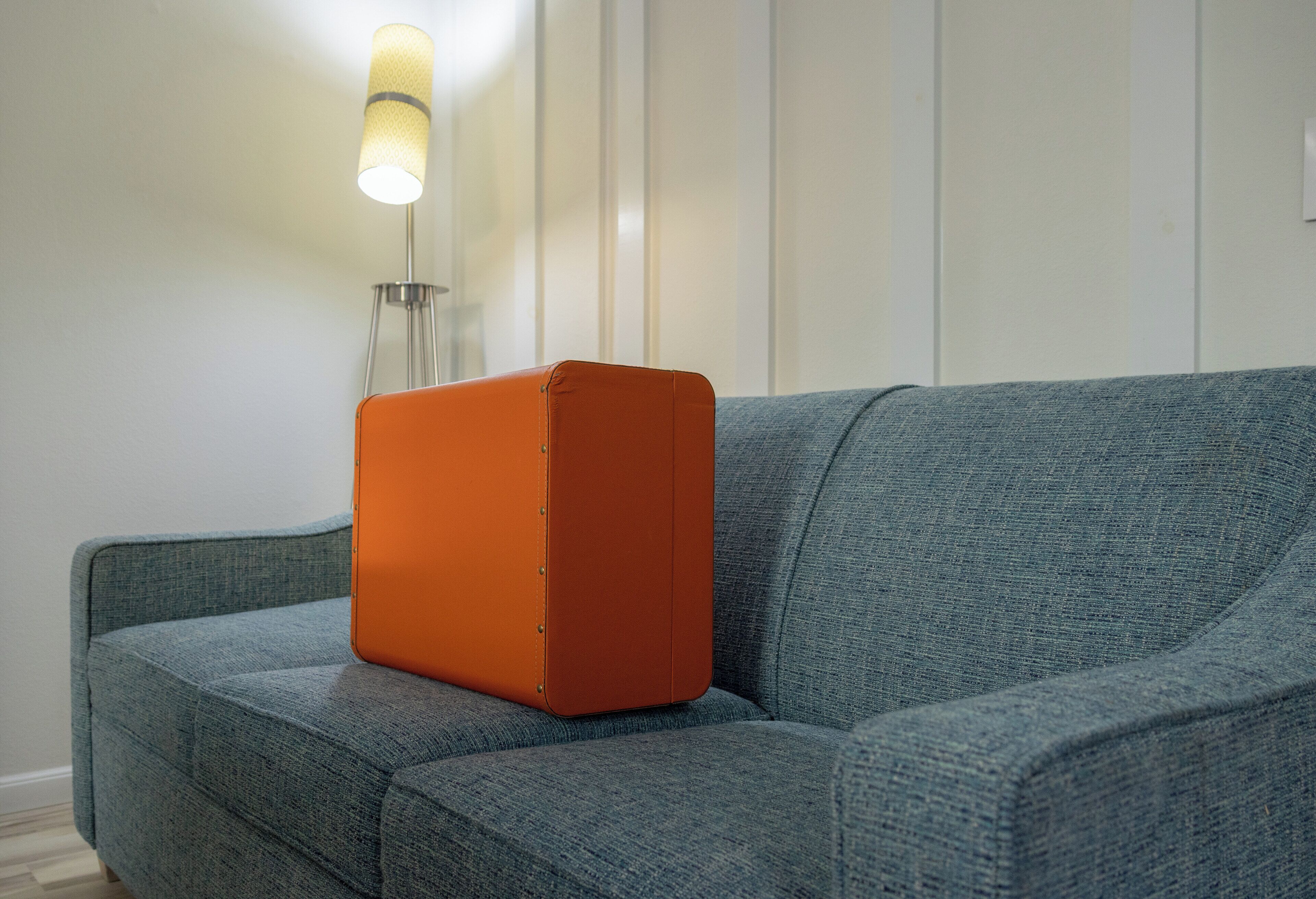 A room with a grey sofa and a small orange object on it.