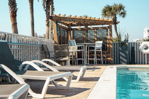 Una piscina al aire libre, sombrillas, sillones reclinables de piscina
