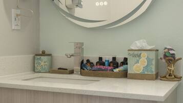 A bathroom with a white countertop, a mirror, and three wicker baskets containing toiletries.