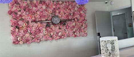 A bathroom with a floral wall art, a clock, a white lamp, and a mirror.