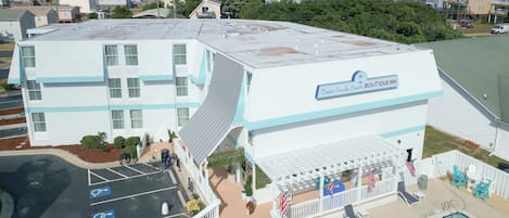 Un edificio a più piani con un cartello che indica 'Ocean Sands Beach Boutique Inn' e un'area piscina con posti a sedere all'aperto.