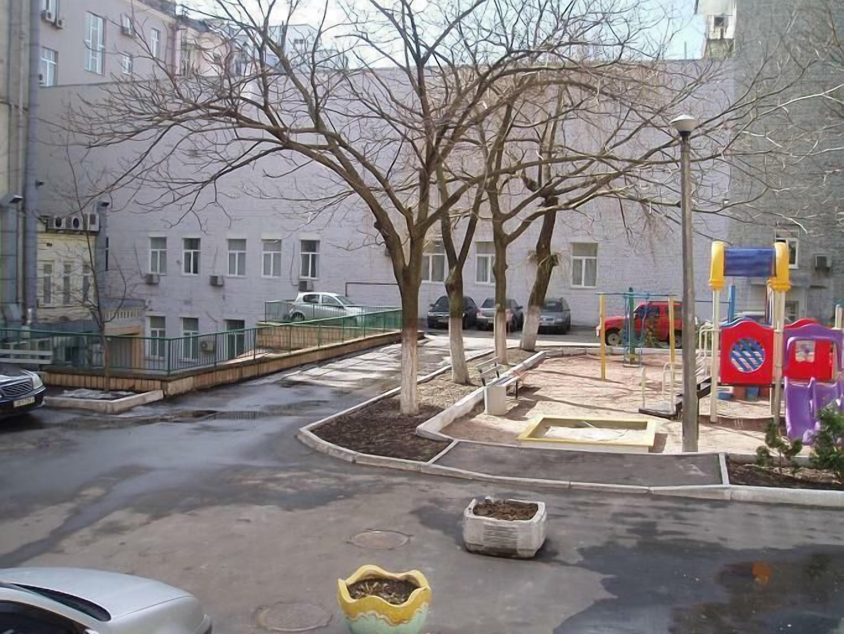 A roundabout with trees, a playground, and a building in the background.