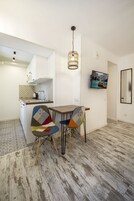 Una cocina compacta con estufa integrada, un lavamanos y una pequeña zona de comedor con dos sillas y una mesa.