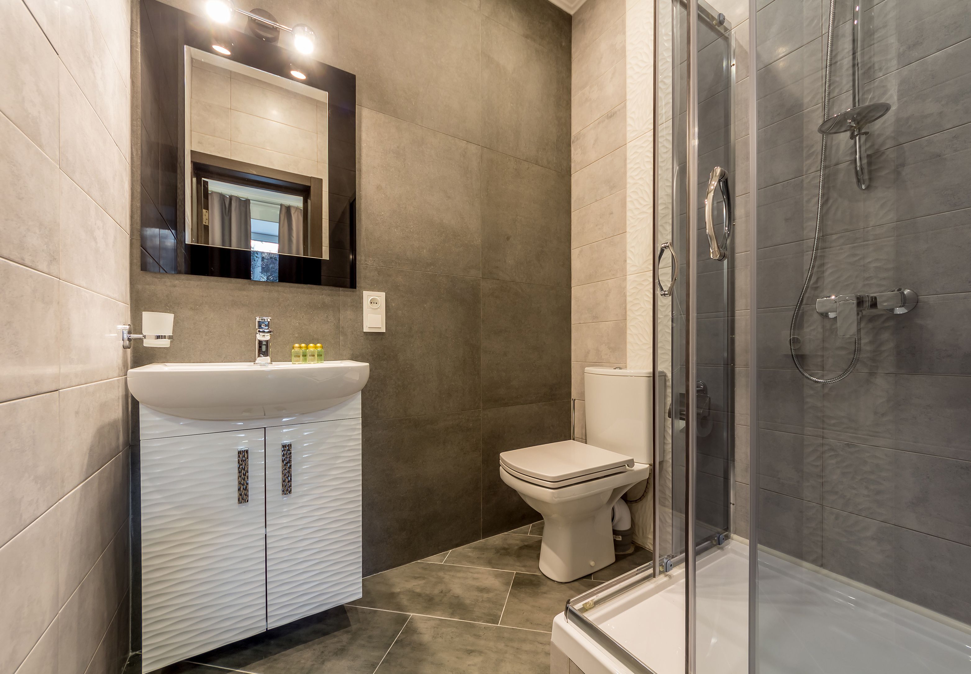 A modern bathroom with a white vanity, a toilet, and a glass-enclosed shower area.