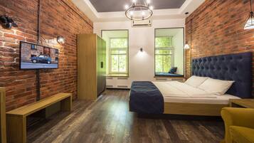 A bedroom with a wooden bed, a bench, a TV on the wall, and a brick wall.