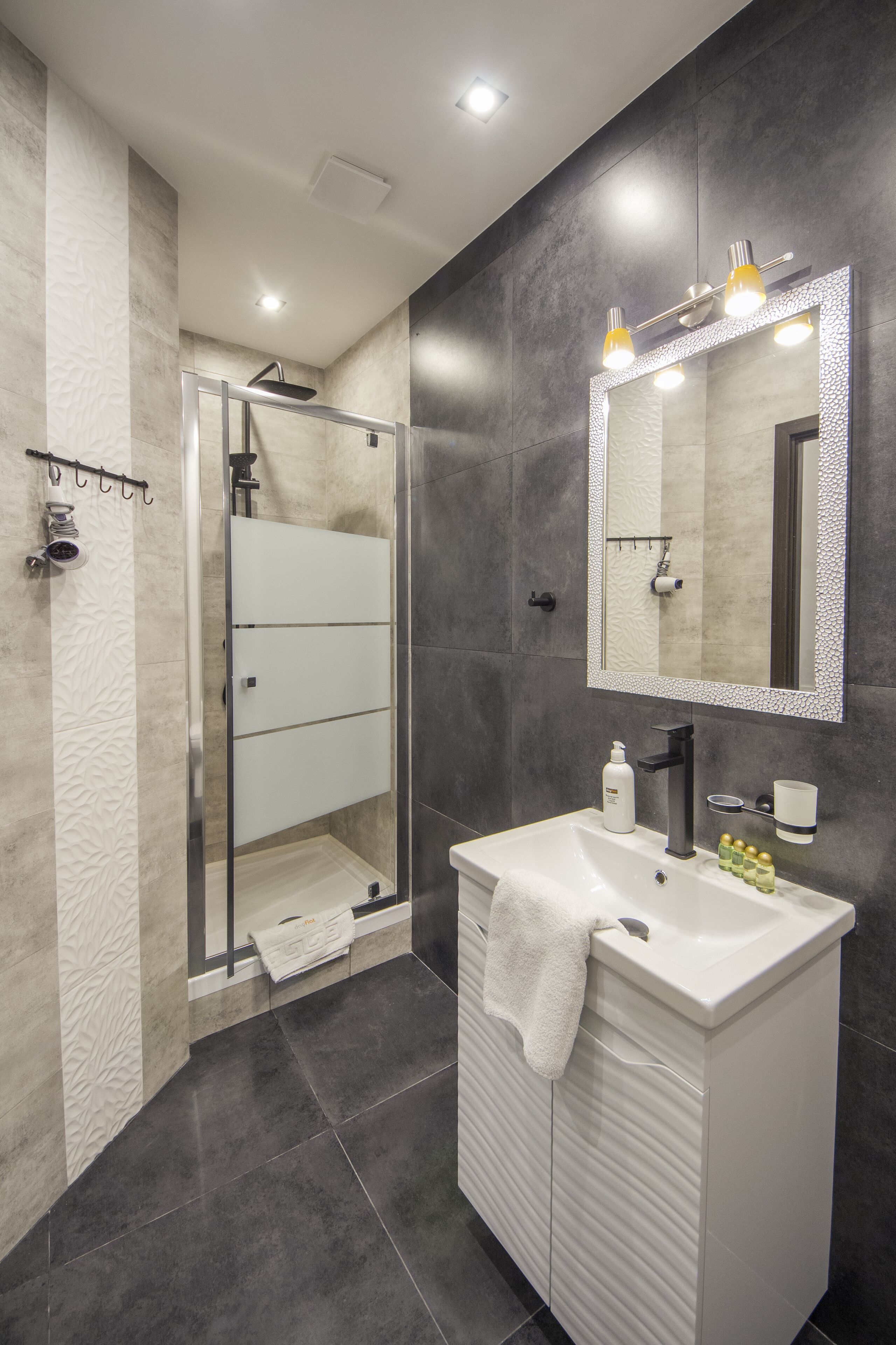 A modern bathroom with a glass-enclosed shower, a white vanity, and a large mirror.