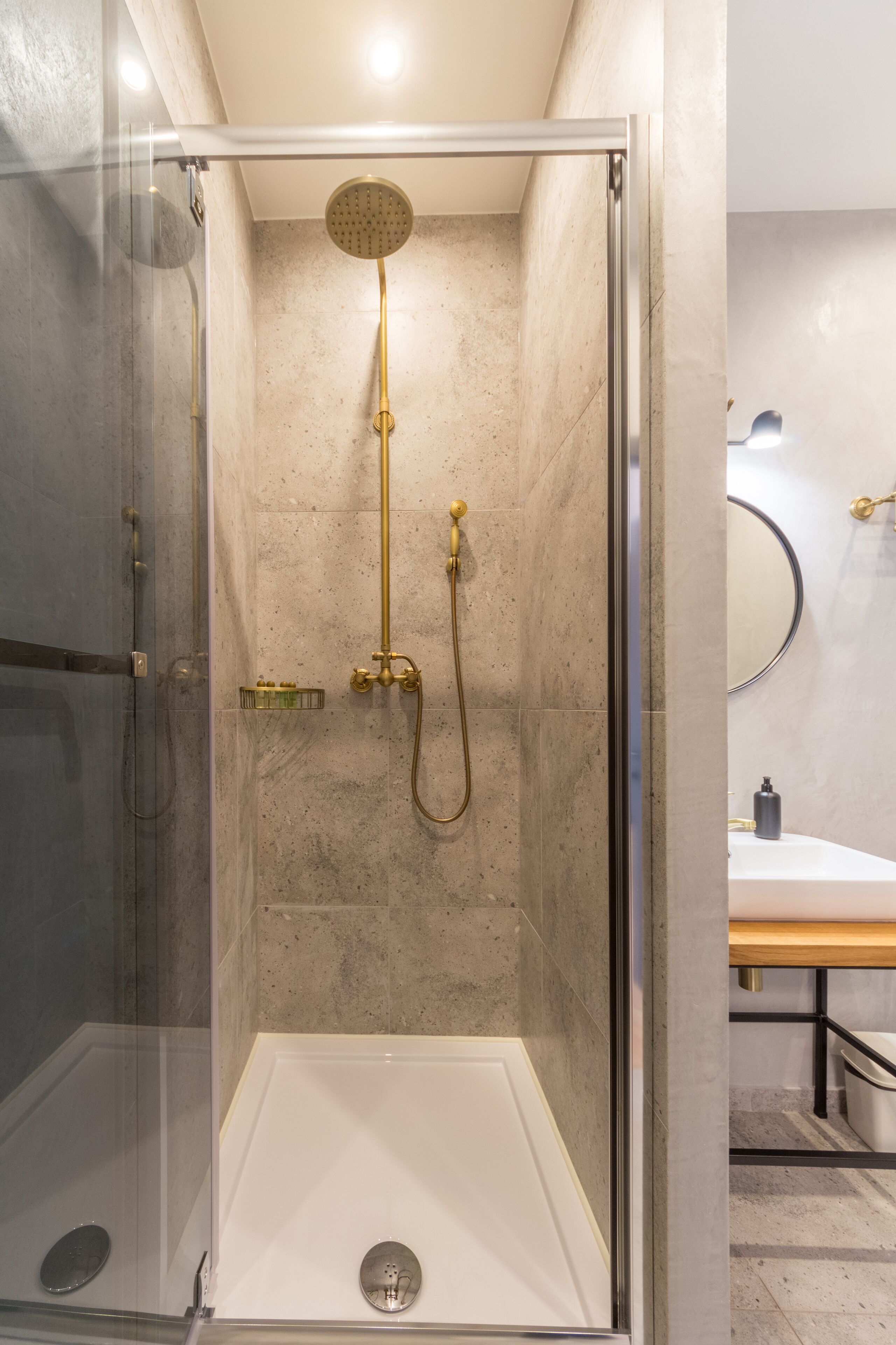 A modern shower enclosure with a glass door, a handheld showerhead, and a wall-mounted faucet.
