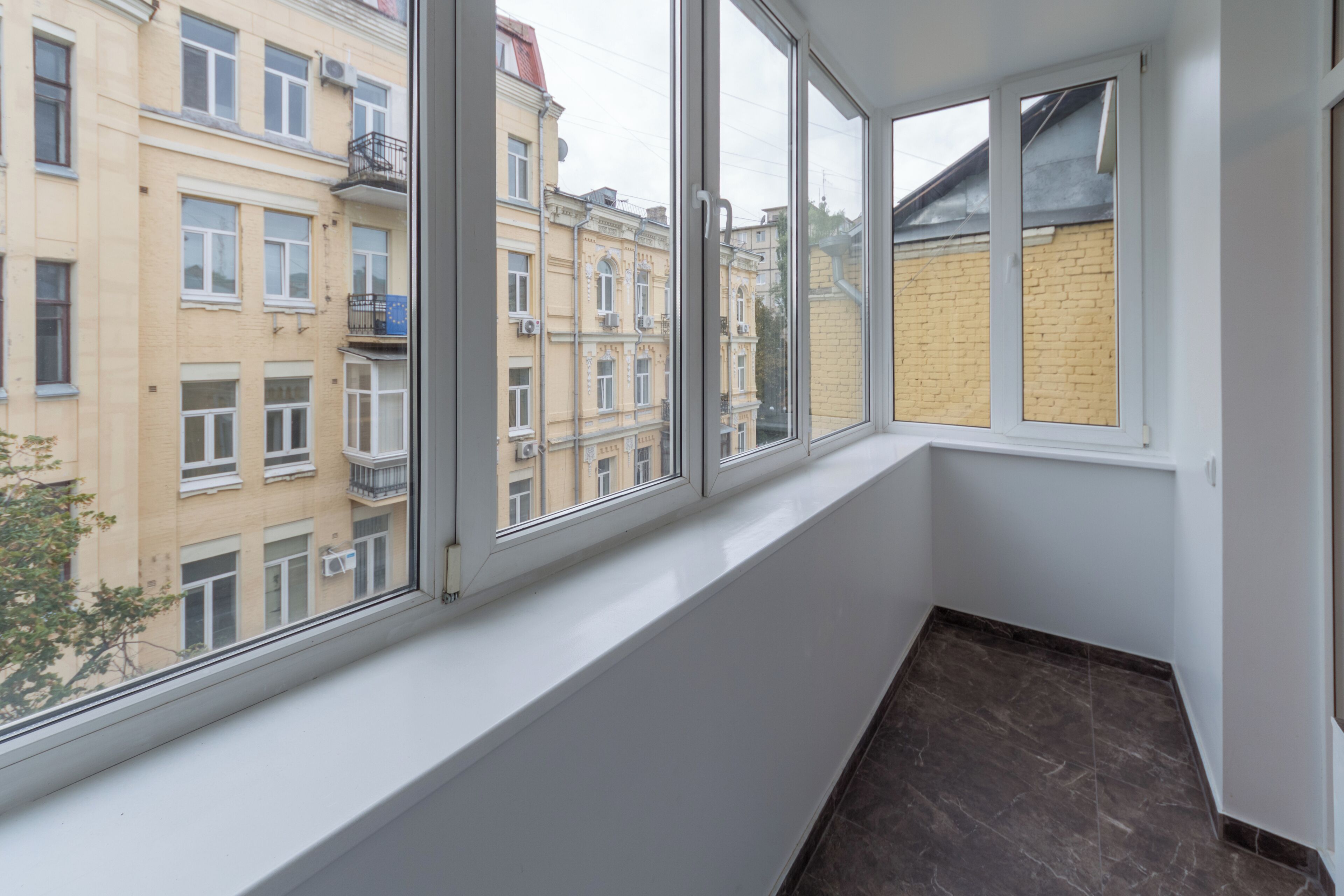 A corner room with large windows overlooking a building with multiple stories and balconies.