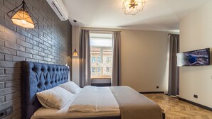 Une chambre d’hôtel moderne avec un mur en briques, un grand lit, une télévision et une fenêtre avec des rideaux.