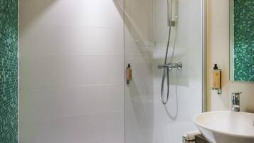 Une salle de bain moderne avec une douche à parois de verre, un lavabo blanc et un mur recouvert de carreaux verts.