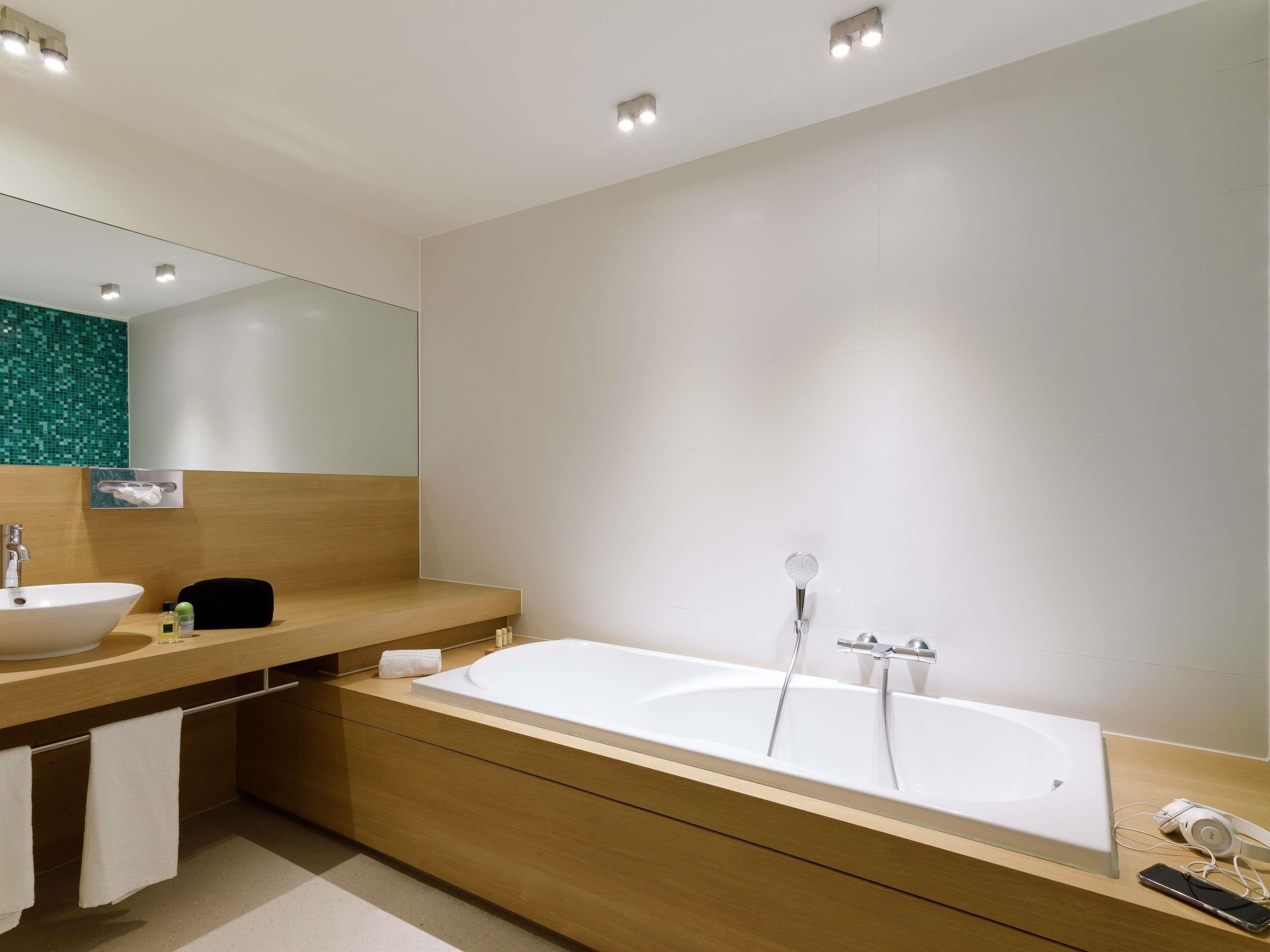 Een moderne badkamer met een vrijstaand bad, een wastafelmeubel en een spiegel.