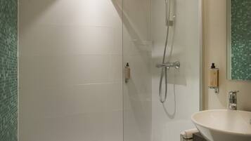 Une salle de bain moderne avec une douche à parois de verre, un lavabo blanc et un miroir.