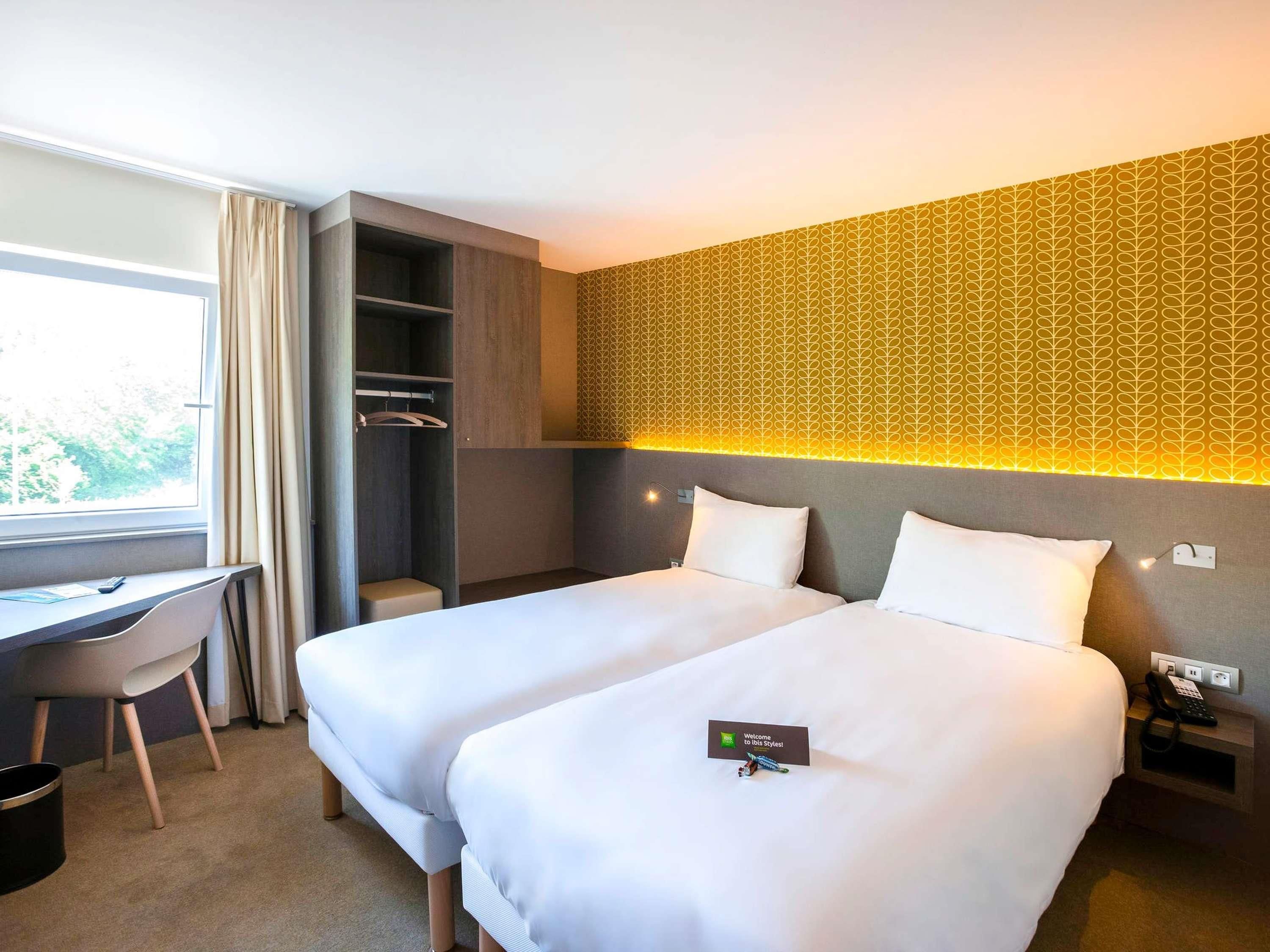 Een hotelkamer met twee bedden, een bureau, een stoel en een kledingkast.