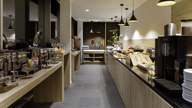 Eine moderne Küche mit Edelstahlgeräten, Holz Arbeitsplatten und Pendelleuchten.
