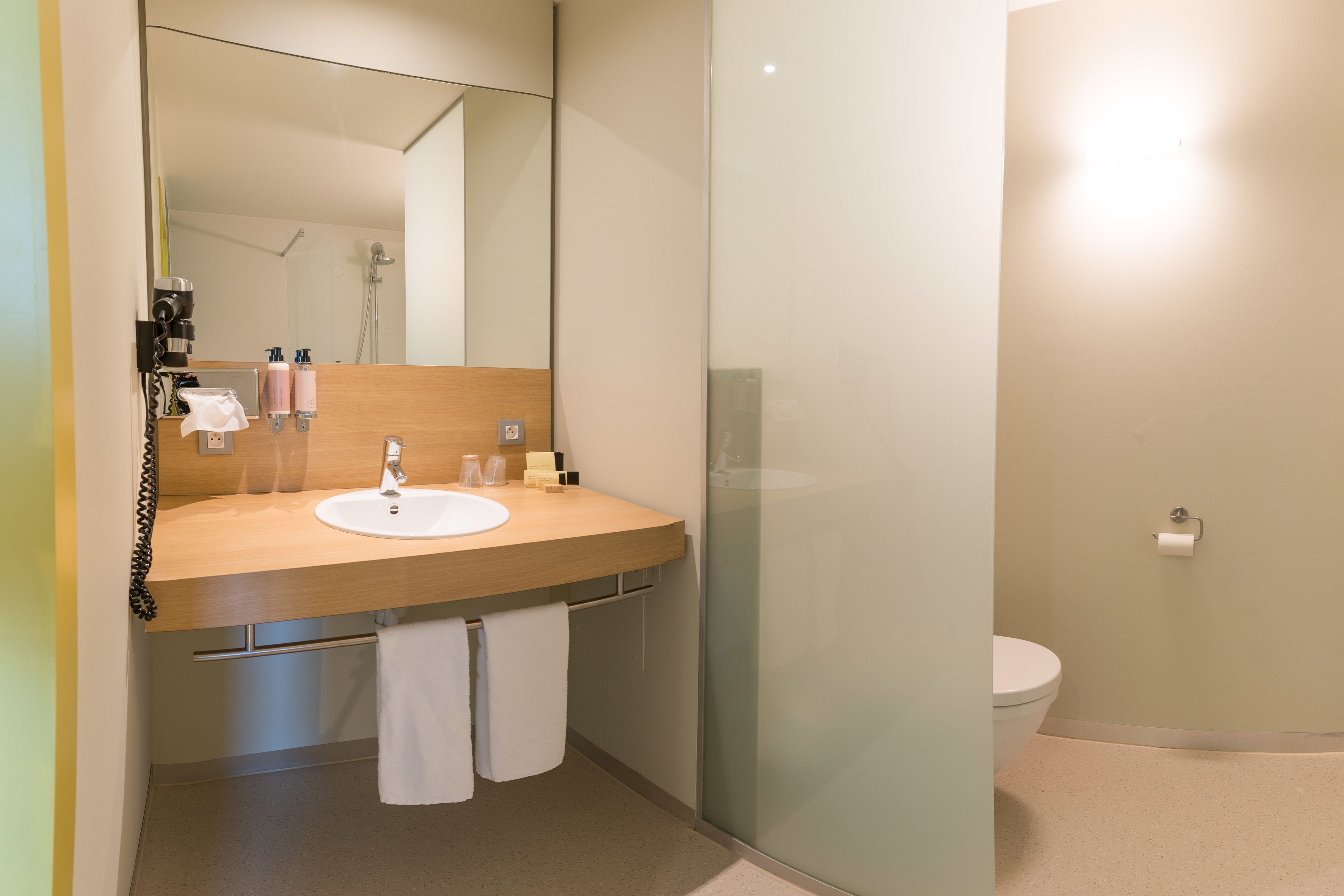 A modern bathroom with a wooden vanity, a mirror, a sink, and a toilet.
