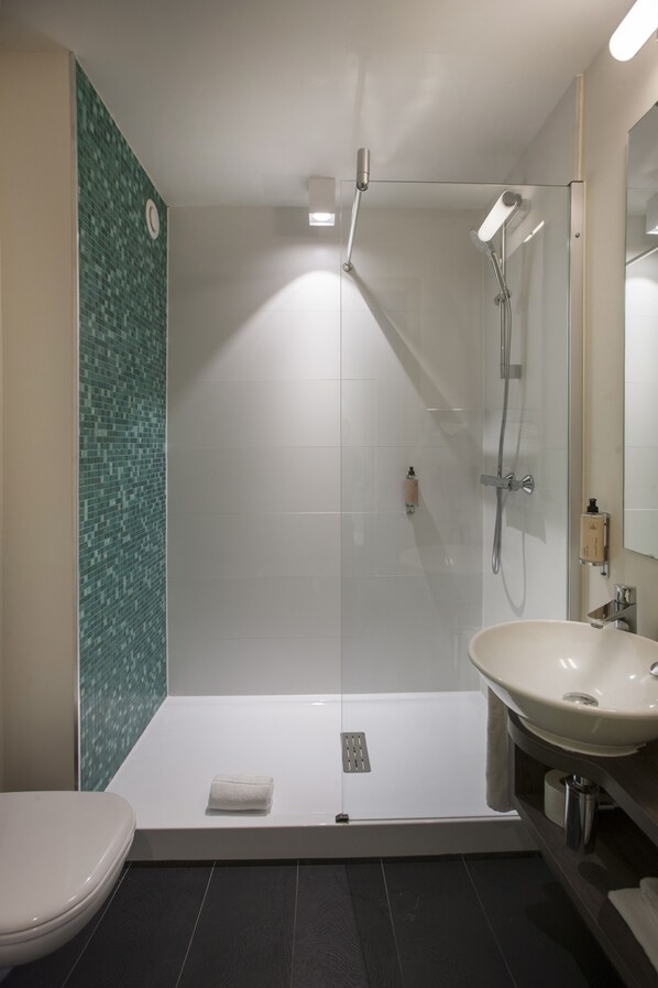Une salle de bain moderne avec une douche à parois de verre, un lavabo blanc et des toilettes.