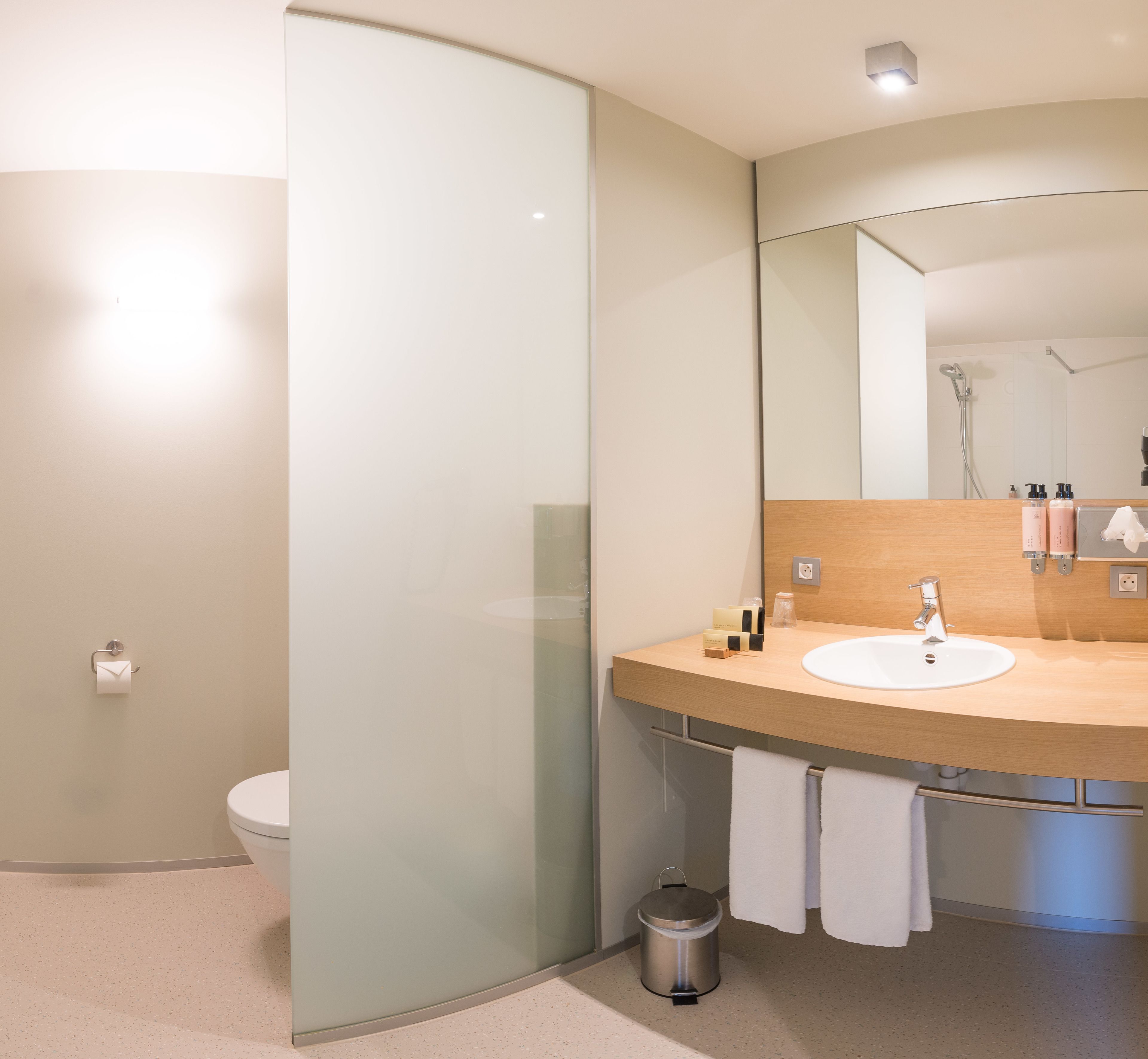 A modern bathroom with a glass shower enclosure, a wooden vanity with a sink, and a mirror above the vanity.