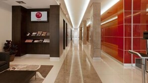 Un pasillo moderno de hotel con una recepción, una pared roja y naranja, y un piso limpio y pulido.