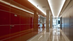 Un pasillo moderno de hotel con taquillas rojas y grises, piso pulido y techo luminoso.