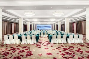 A conference room with rows of tables and chairs, a carpet with a floral pattern, and a view of the sky through a window. - Ganjiang Hotel (Nanchang)