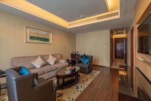 A modern living room with a sofa, armchairs, a coffee table, and a TV.