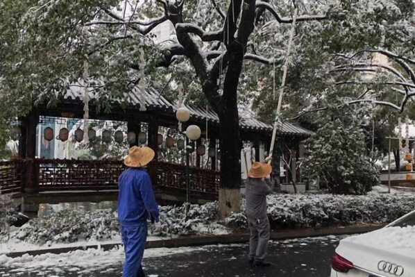A traditional pavilion with a tiled roof, surrounded by snow-covered trees and a pathway.