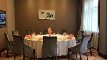 A conference room with a round table, chairs, and a television mounted on the wall.