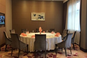 A conference room with a round table, chairs, and a television mounted on the wall. - Ganjiang Hotel (Nanchang)