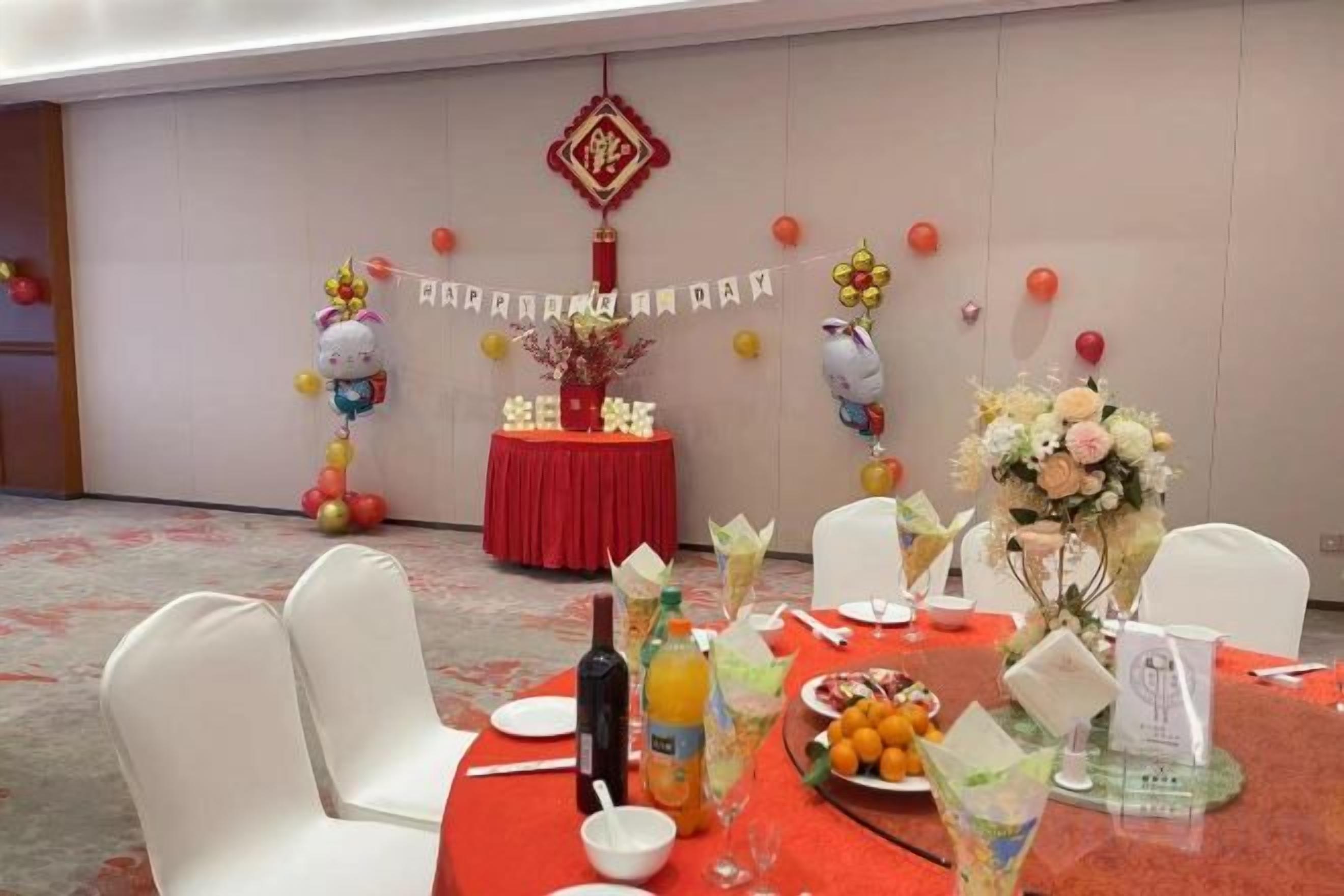 Un salón de banquetes con mesas redondas, sillas y alfombra roja.