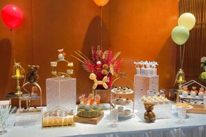 A table with various food and drink items, including desserts and beverages, arranged on a white tablecloth. - Ganjiang Hotel (Nanchang)